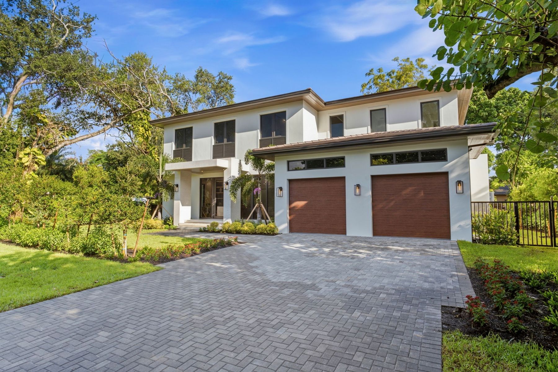 Front of 6255 SW 69th Street: a white two-story contemporary home with a two-car garage and paver driveway under mature trees